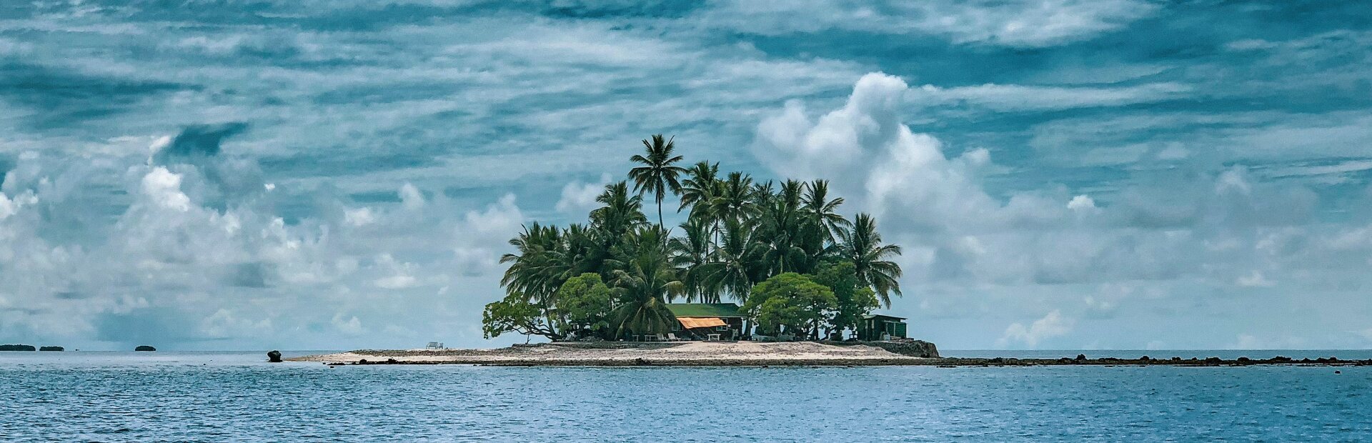 Insel mit Palmen im Meer, Wolken am Himmel